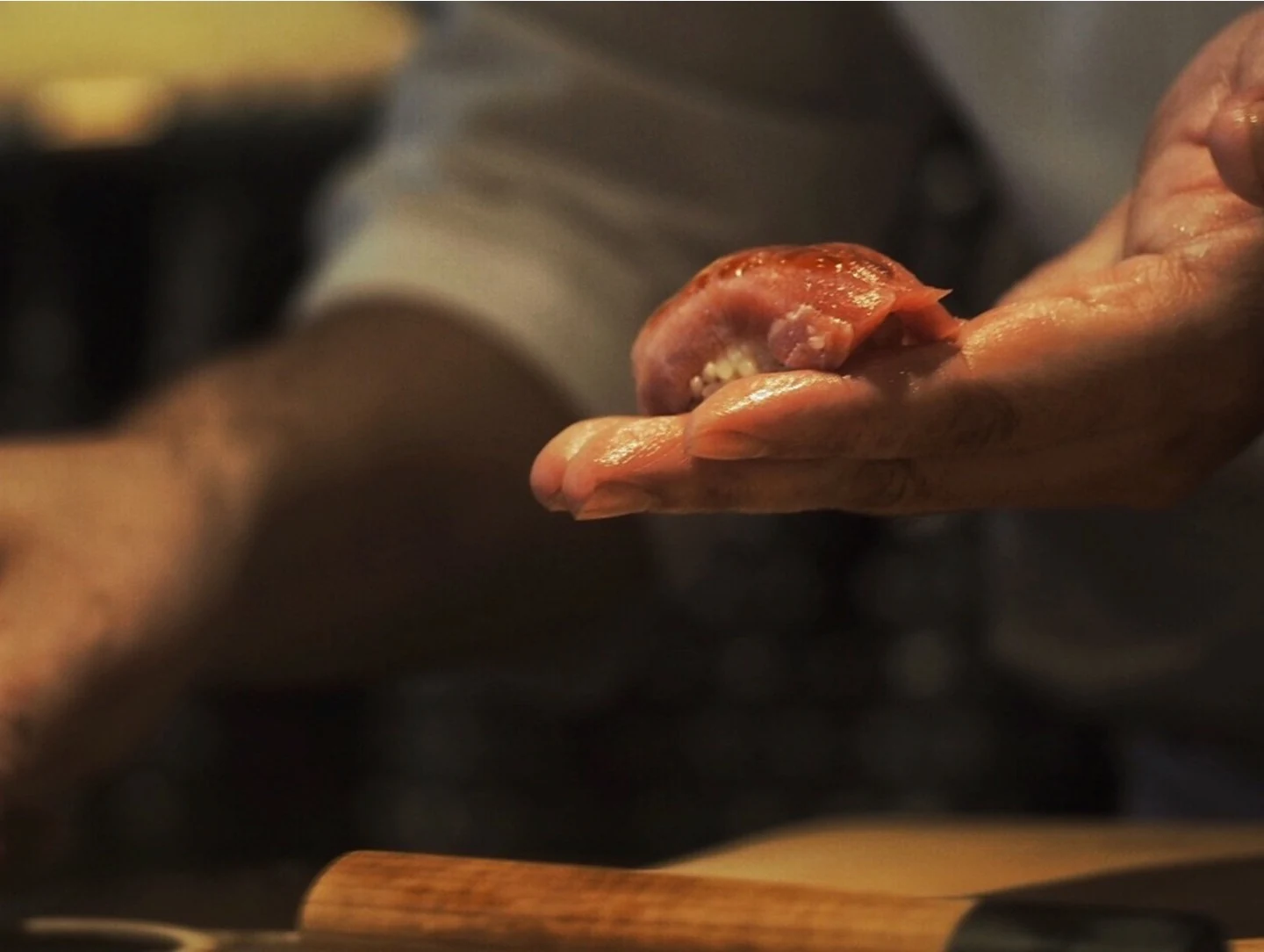 A chef shaping sushi by hand, expressing precision, craft and the intimate theatre of culinary preparation.