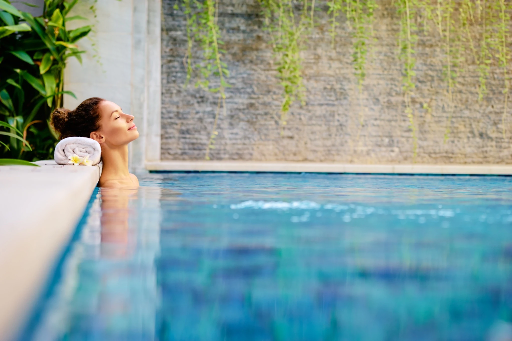 Guest relaxing in a tranquil spa pool surrounded by greenery.